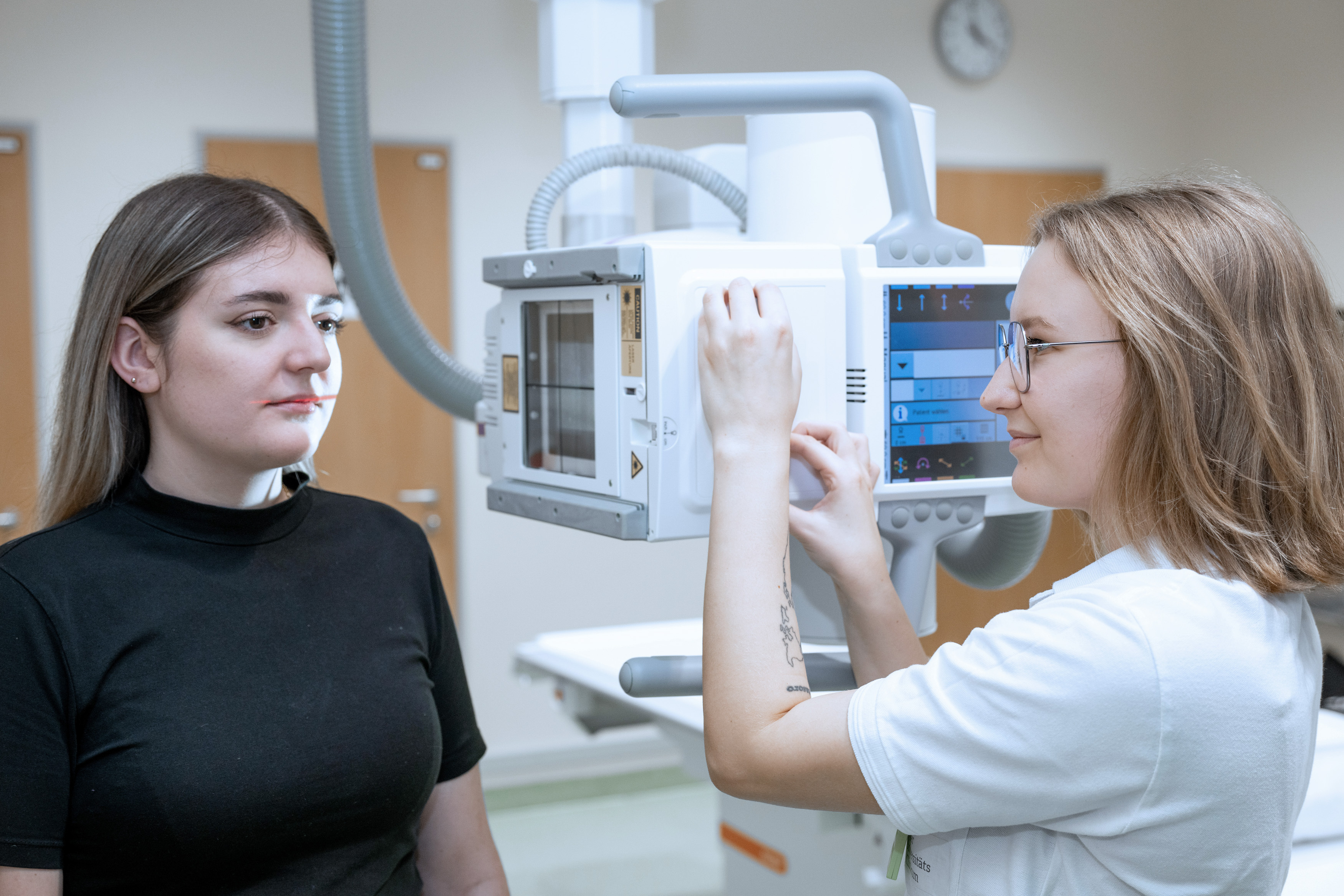 Radiologietechnologin beim Einrichten des Röntgengeräts an der Patientin 