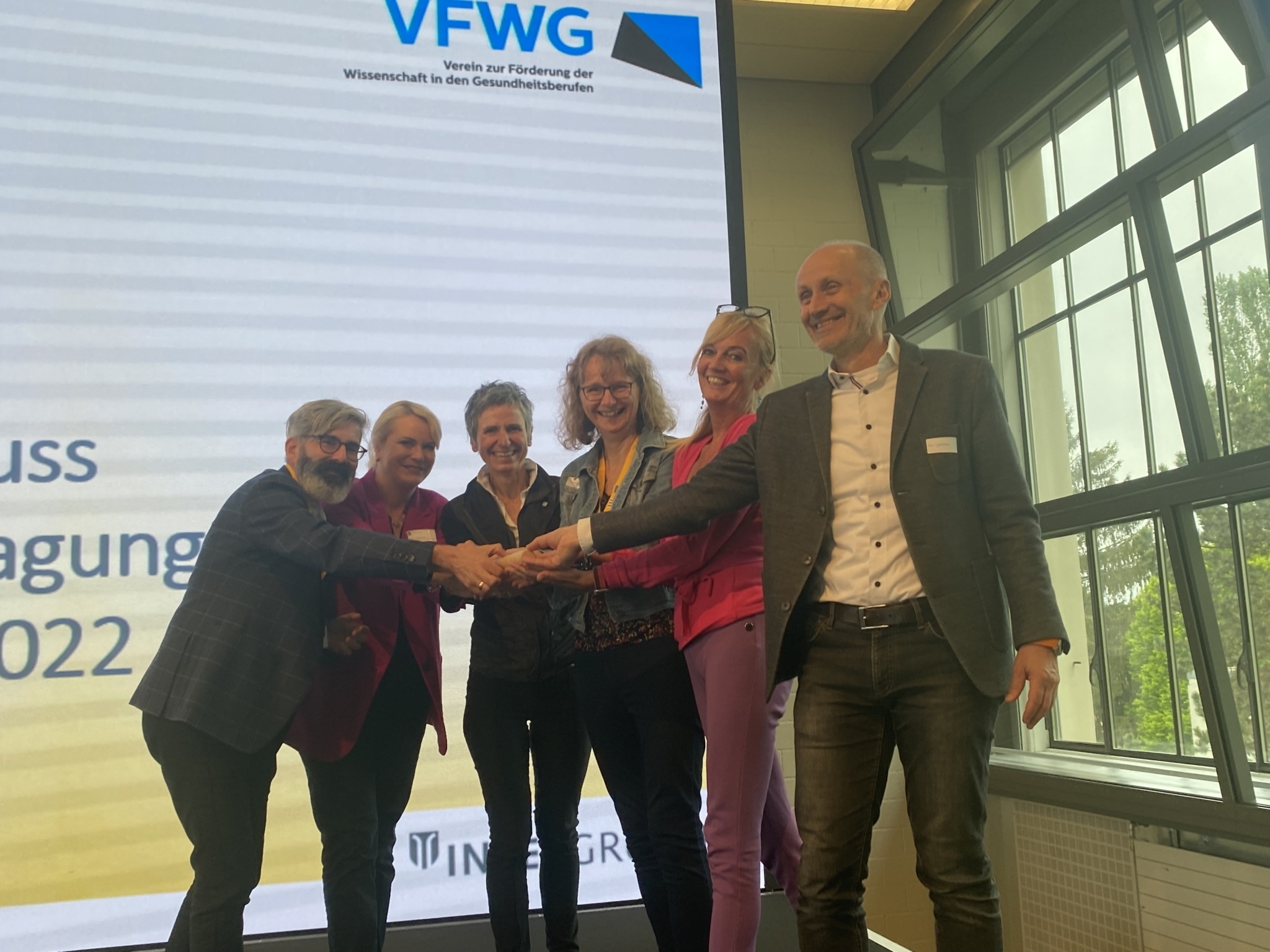 Stabübergabe bei der 3 Ländertagung 2022 (Präsident VFWG, Prof. Dr. Andreas Gerber-Grote; Verantwortliche Tagungsorganisation Prof. Dr. Sabine Hahn, Team der FH Gesundheitsberufe OÖ) 