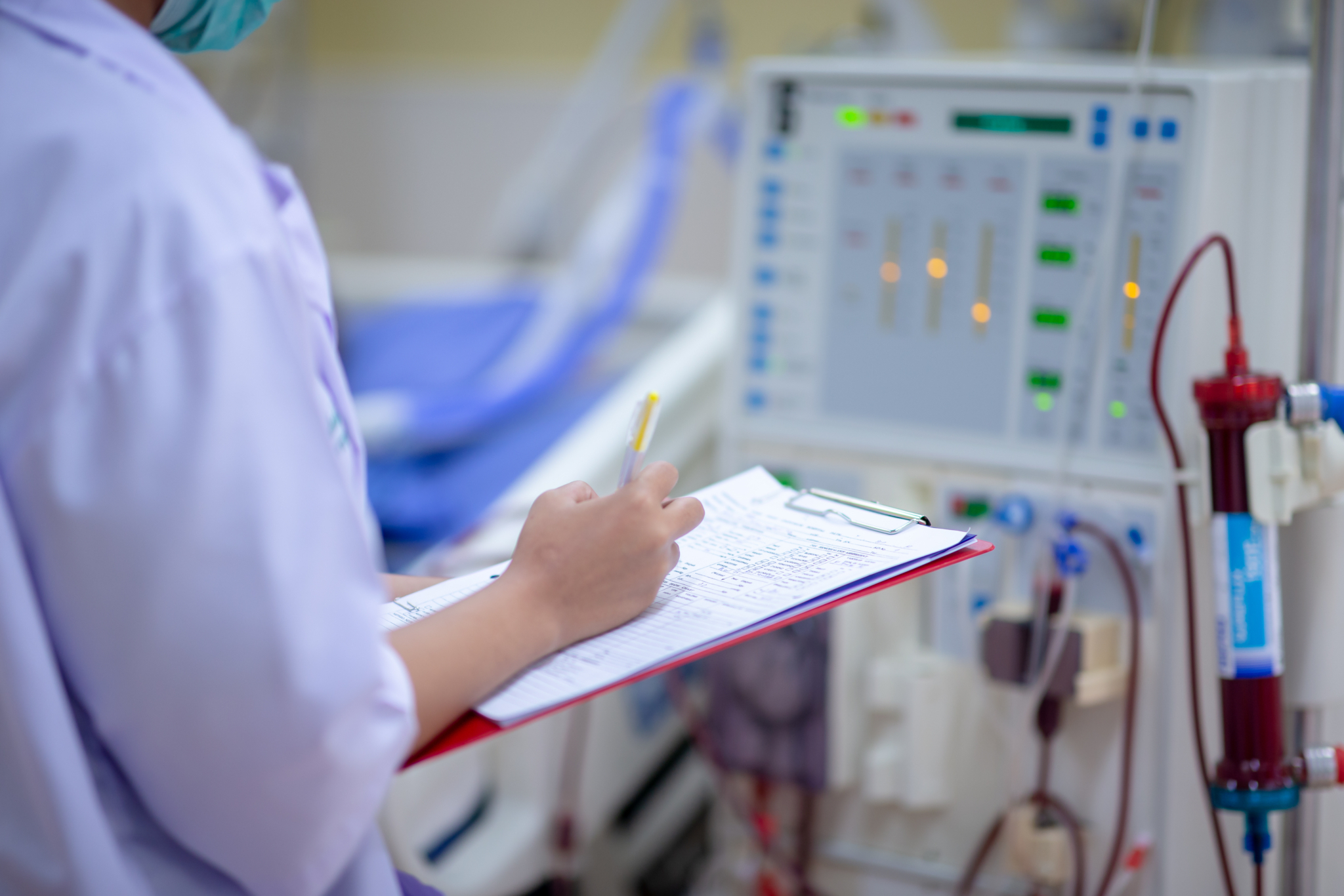 Krankenpfleger*in bei der Kontrolle der Dialyse mit einem Klemmbrett Krankenpfleger*in bei der Kontrolle der Dialyse mit einem Klemmbrett