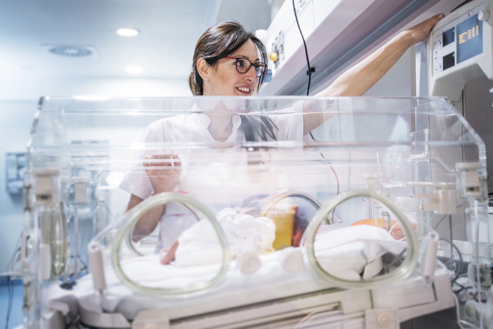 Kinderintensivpfleger*in beim hantieren im Inkubator 