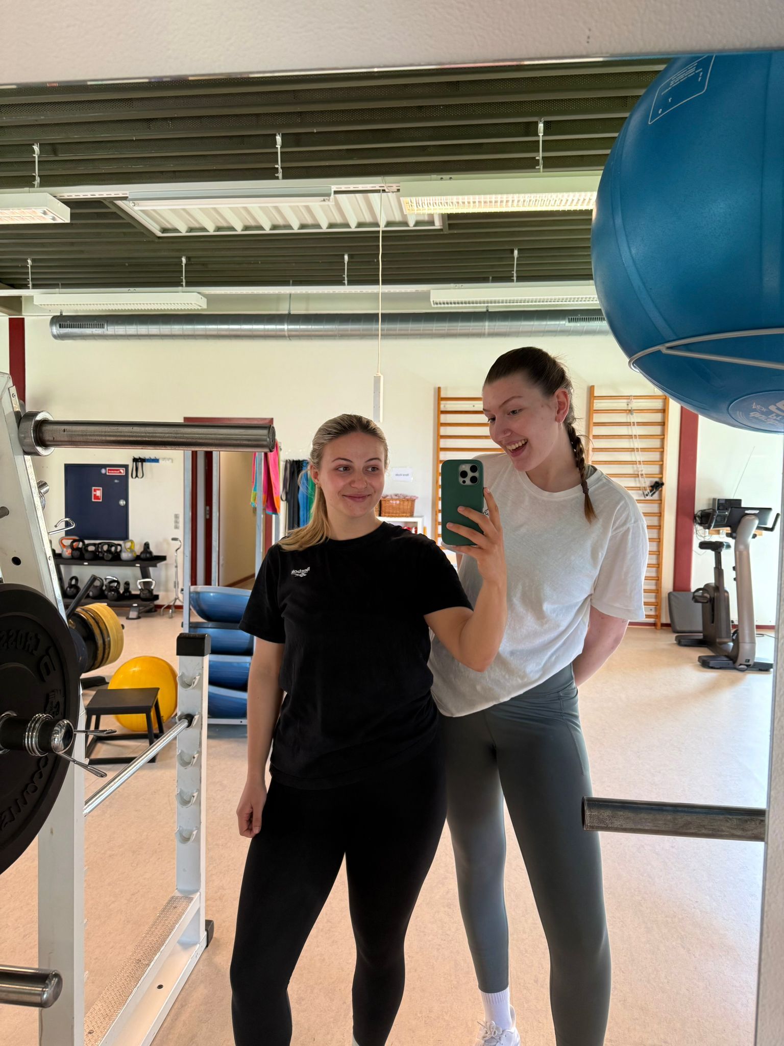 Die beiden Physiotherapie Studierenden Lara Mendl und Celia Lechner bei einem Selfie vor einem Spiegel im Gym. 